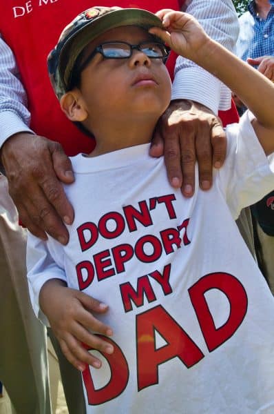 A young boy joins faith leaders and activists in a protest against immigrant deportations in front of the White House in Washington, D.C., on July 31, 2014.