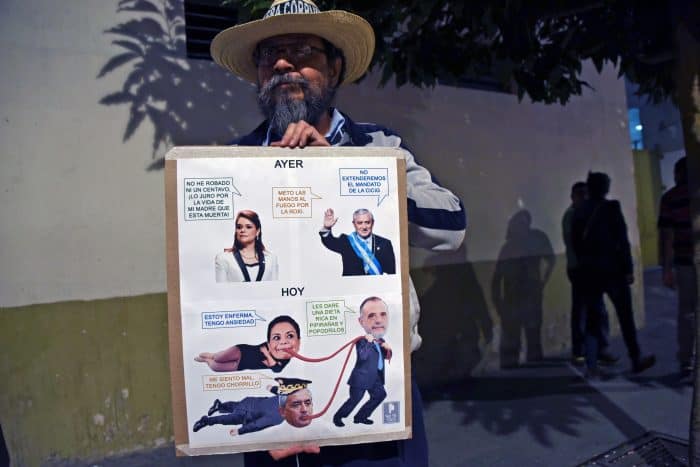 A man holds a sign with pictures of Guatemalan President Otto Pérez Molina, ex-Vice President Roxana Baldetti and the chief of the International Commission Against Impunity in Guatemala, Iván Velásquez.