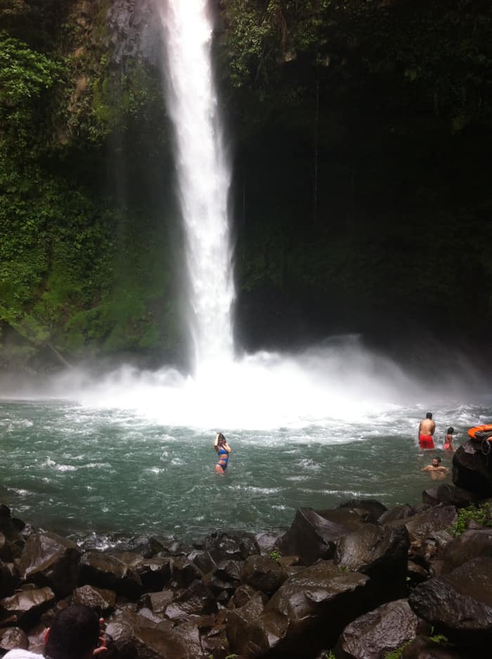 A woman strikes a pose in front of La Fortuna Waterfall.