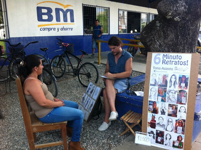 The man's partner is persuaded to sit for her portrait.