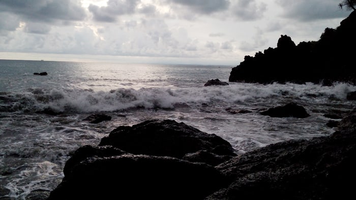 Waves crash on rocks as the day wanes.