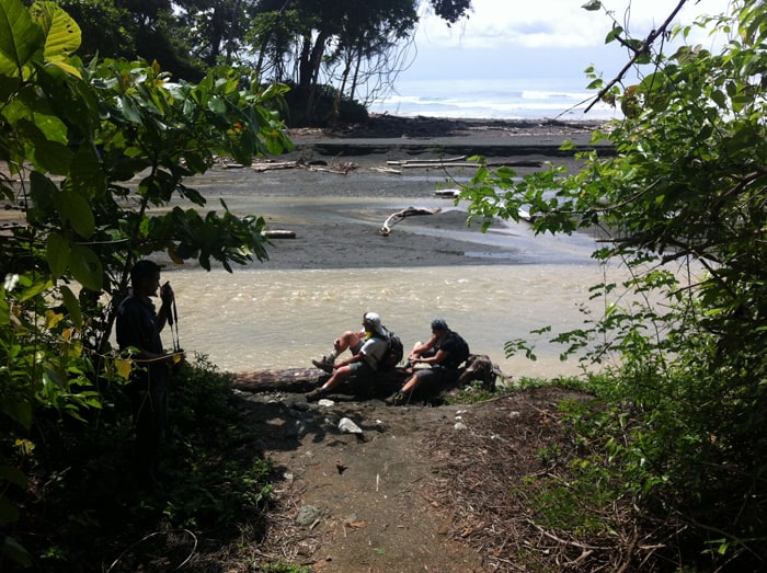 Jim and Shannon take a breather in the sun next to the Río Madrigal, putting their shoes back on.