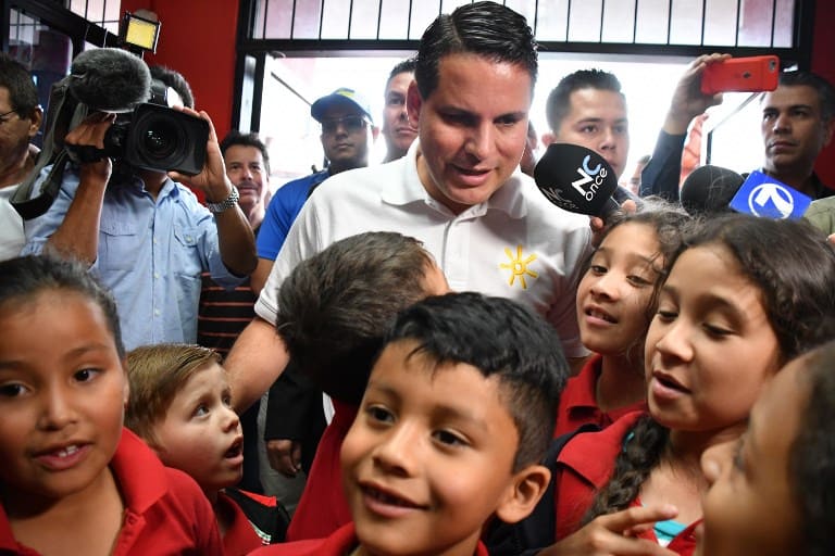 Costa Rican presidential candidate, Fabricio Alvarado, of the National Restoration Party (PRN), is surrounded by children during his visit to the headquarters of the nonprofit organization Works of the Holy Spirit, in San Jose on March 31, 2018, on the eve of country's runoff election.